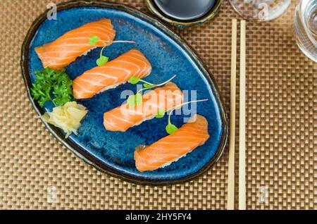 Deliziosa nigiri di salmone di prima qualità su piatto blu fatto a mano decorato Foto Stock