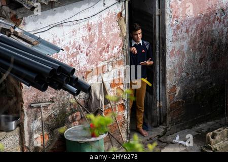 Il giovane cubano che indossa la divisa della sua scuola si trova all'ingresso della sua casa, controllando la dolce pioggia che cade dalle nuvole. Foto Stock