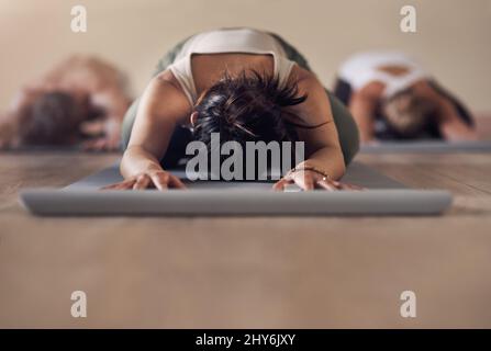 Lo yoga è il nostro stile di vita. Shot di un gruppo di persone irriconoscibili che meditano e si allenano insieme in una lezione di yoga. Foto Stock
