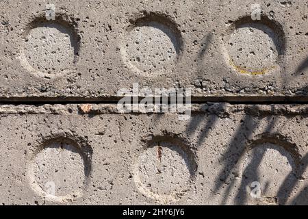 Struttura lineare di vecchie lastre di cemento grigio blocco con fori impilati l'uno sopra l'altro primo piano vista laterale. Materiale invecchiato, costruzione. Brutale backgr Foto Stock