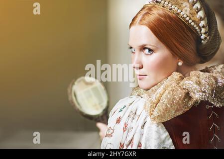 Chi è il più bello di tutti. Scatto di un'elegante nobile donna ammirando se stessa in uno specchio nella sua stanza del palazzo. Foto Stock