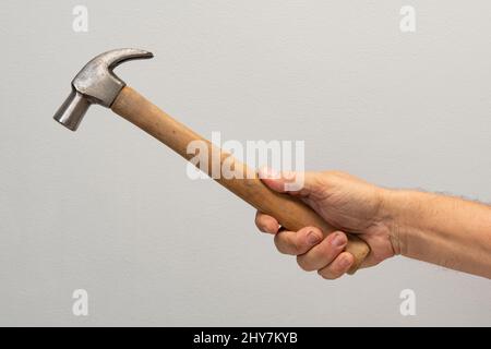 La mano dell'uomo tiene uno strumento isolato su sfondo grigio. Foto Stock