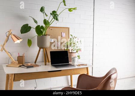 Scrivania da ufficio con lampada e computer portatile. Foto Stock