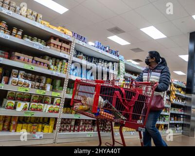 Kirkland, WA USA - circa Febbraio 2022: Donna indiana con gli occhiali shopping nel corridoio di verdure in scatola all'interno di un negozio di alimentari Trader Joe. Foto Stock