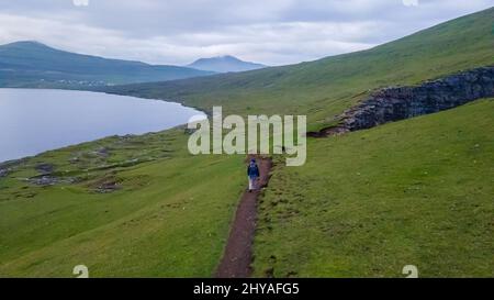 Splendida vista aerea della cascata di Bøsdalafossur e dei magnifici monumenti di Trælanípan nelle Isole Faroe Foto Stock