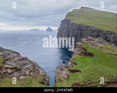 Splendida vista aerea della cascata di Bøsdalafossur e dei magnifici monumenti di Trælanípan nelle Isole Faroe Foto Stock