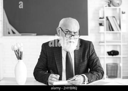 Professore tenendo un libro e indicando con un bastone di legno isolato su sfondo bianco. Conoscenza e concetto di istruzione tradizionale. Foto Stock