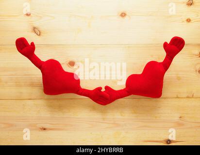 Primo piano di cuori morbidi con due mani isolate su sfondo rustico in legno Foto Stock