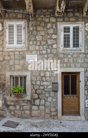 Vecchia porta in legno intemperie, finestre e muri in pietra nella Città Vecchia di Dubrovnik, Croazia. Foto Stock