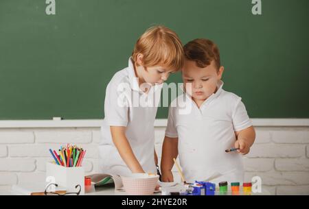 I capretti della scuola del ritratto bosy che fanno i compiti di arte, la matita di tenuta, la scrittura. Bambini alunni che fanno scuola elementare. Lezione di pittura, disegno Foto Stock