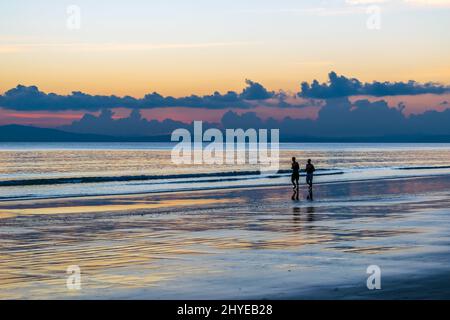 Coppia sulla spiaggia al tramonto Foto Stock