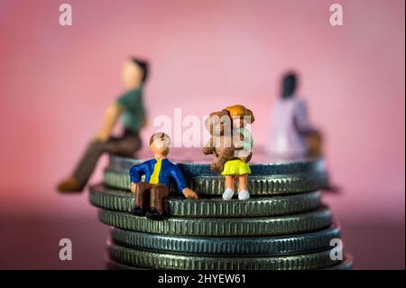 Persone in miniatura. Fratello e sorella seduti da soli. Genitori in background. Concetto di rottura della famiglia, divorzio. Programma di visita Foto Stock