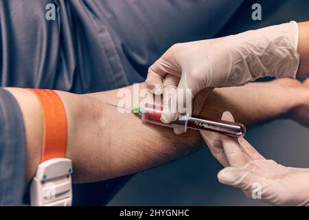 Paziente di sesso maschile durante la procedura di campionamento dell'analisi del sangue Foto Stock