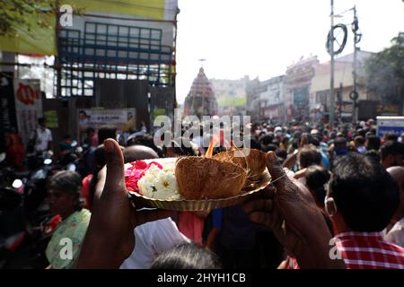 Chennai, Tamil Nadu, India. 15th Mar 2022. I devoti indù offrono preghiere come un carro decorato con fiori e statue che portano una divinità di Dio indù Shiva passa vicino durante una processione annuale del festival dell'automobile del tempio a Chennai. (Credit Image: © Sri Loganathan/ZUMA Press Wire) Foto Stock