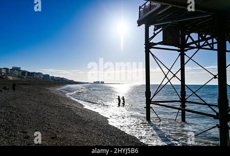 Brighton UK 7th Marzo 2022 - nuotatori di prima mattina da Brighton Palace Pier in una bella giornata di sole con le previsioni del tempo caldo per diffondersi in tutta la Gran Bretagna nei prossimi giorni: Credit Simon Dack / Alamy Live News Foto Stock