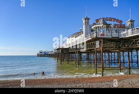 Brighton UK 7th Marzo 2022 - nuotatori di prima mattina da Brighton Palace Pier in una bella giornata di sole con le previsioni del tempo caldo per diffondersi in tutta la Gran Bretagna nei prossimi giorni: Credit Simon Dack / Alamy Live News Foto Stock