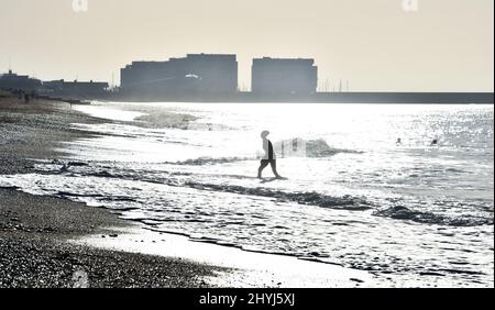 Brighton UK 7th Marzo 2022 - un nuotatore di prima mattina sulla spiaggia di Brighton in una bella giornata di sole con le previsioni del tempo caldo per diffondersi in tutta la Gran Bretagna nei prossimi giorni: Credit Simon Dack / Alamy Live News Foto Stock