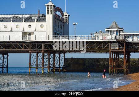 Brighton UK 7th Marzo 2022 - nuotatori di prima mattina da Brighton Palace Pier in una bella giornata di sole con le previsioni del tempo caldo per diffondersi in tutta la Gran Bretagna nei prossimi giorni: Credit Simon Dack / Alamy Live News Foto Stock