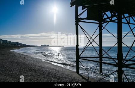 Brighton UK 7th Marzo 2022 - un nuotatore di prima mattina da Brighton Palace Pier in una bella giornata di sole con le previsioni del tempo caldo per diffondersi in tutta la Gran Bretagna nei prossimi giorni: Credit Simon Dack / Alamy Live News Foto Stock