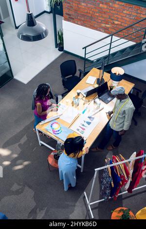 Vista ad alto angolo di stilisti multirazziali maschili e femminili che lavorano alla scrivania Foto Stock