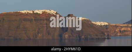 Vista da Oia sulla caldera alle scogliere, Imerovigli, Firostefani, Fira, villaggi sulle scogliere, cielo azzurro e nuvoloso, mare calmo e scuro Foto Stock