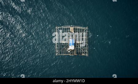 Un kelong è la cosa più vicina a lavorare da casa. Colpo ad angolo alto di una struttura di pesca costruita che galleggia nel mezzo dell'oceano chiamato un kelong. Foto Stock