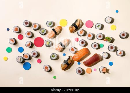 Set di sushi roll. Sushi e panini tradizionali giapponesi con salmone fresco, tonno, anguilla e gamberi su riso, cerchi colorati su sfondo beige con Foto Stock