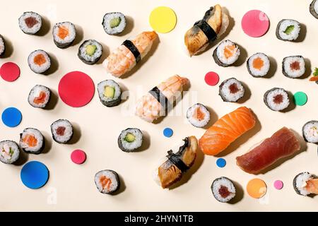 Set di sushi roll. Sushi e panini tradizionali giapponesi con salmone fresco, tonno, anguilla e gamberi su riso, cerchi colorati su sfondo beige con Foto Stock