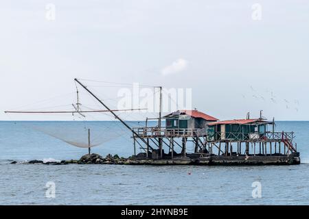 Gabbiani che volano su un tradizionale capanno da pesca a trebucco, Marina di Pisa, Italia Foto Stock