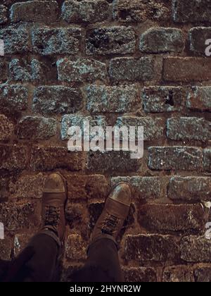 Vista dall'alto dei piedi su un terreno in pietra di mattoni Foto Stock