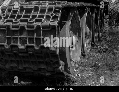 Primo piano, scatto monocromico delle ruote dei cingoli di un veicolo Foto Stock