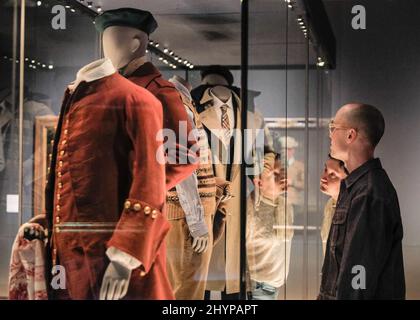 Londra, Regno Unito. 15th Mar 2022. EMBARGED fino al 16 marzo, 00,01 GMT. Il personale guarda una collezione di abiti da uomo storici. La nuova mostra del V&A "Masculinities alla moda: The Art of Menswear" presenta circa 100 look di designer leggendari e stelle emergenti, tra cui Harris Reed, Gucci, Grace Wales Bonner e Raf Simons, oltre a 100 opere d'arte su un'ampia gamma di media. Credit: Imagplotter/Alamy Live News Foto Stock