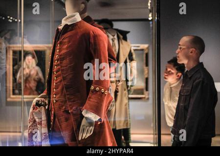 Londra, Regno Unito. 15th Mar 2022. EMBARGED fino al 16 marzo, 00,01 GMT. Il personale guarda una collezione di abiti da uomo storici. La nuova mostra del V&A "Masculinities alla moda: The Art of Menswear" presenta circa 100 look di designer leggendari e stelle emergenti, tra cui Harris Reed, Gucci, Grace Wales Bonner e Raf Simons, oltre a 100 opere d'arte su un'ampia gamma di media. Credit: Imagplotter/Alamy Live News Foto Stock