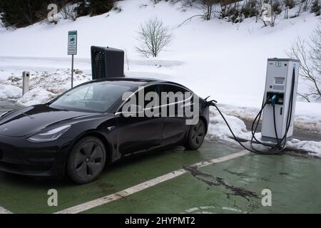 Brennero, Italia - 18 febbraio 2022: Uno scatto statico di una carica awd a lungo raggio a doppio motore Tesla modello 3 a nero solido alla carica rapida CC in una nuvola Foto Stock