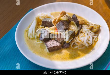 Spaghetti di riso lievemente fermentati o Cheen Kanom in lingua thailandese, spaghetti con pollo al curry verde e sangue di pollo in streaming, cibo in roun bianco Foto Stock