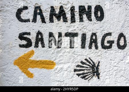 Segno Camino De Santiago con la tradizionale freccia gialla e conchiglia che dirige il pellegrino sul percorso Foto Stock