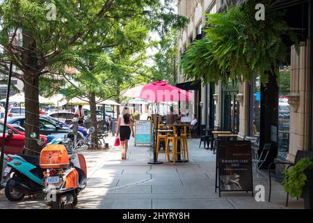 ASHEVILLE, NC, USA-22 LUGLIO 2021: Una giornata estiva su Page Ave. In centro, mostrando la gente ai tavoli da caffè marciapiede, una donna ben vestita a piedi. Foto Stock