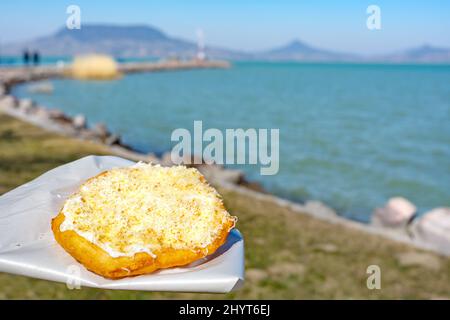 Tipico lago ungherese Balaton cibo langos con sfondo lago a Fonyod Foto Stock