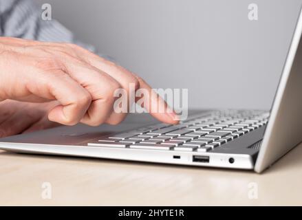 Man mano primo piano premendo il tasto invio. Uomo seduto al tavolo e che lavora su un computer portatile. Foto di alta qualità Foto Stock