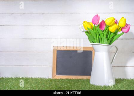 Biglietto d'auguri per il giorno della mamma. Tulipani bouquet in vaso e cartellino di saluto su legno bianco e legno plank sfondo spazio copia Foto Stock