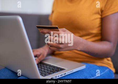 Un primo piano di una giovane donna in possesso di una carta di credito e shopping online Foto Stock