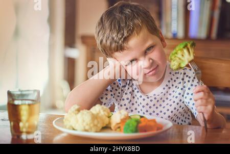 Theres nessun senso im che mangia questa roba. Ritratto di un ragazzino disgustato che rifiuta di mangiare le verdure al tavolo da pranzo. Foto Stock