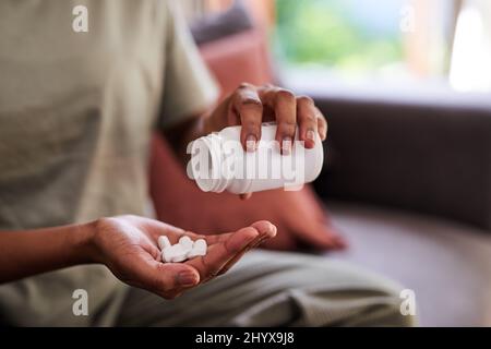Un primo piano di mani che versano pillole da una bottiglia Foto Stock