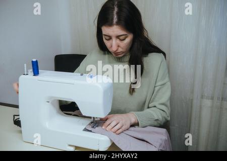 la donna sews su una macchina da scrivere a casa Foto Stock