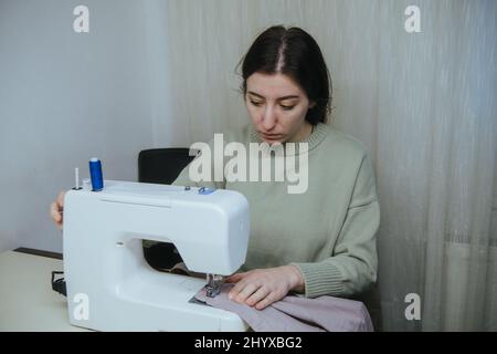 la donna sews su una macchina da scrivere a casa Foto Stock