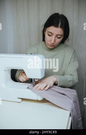 la donna sews su una macchina da scrivere a casa Foto Stock