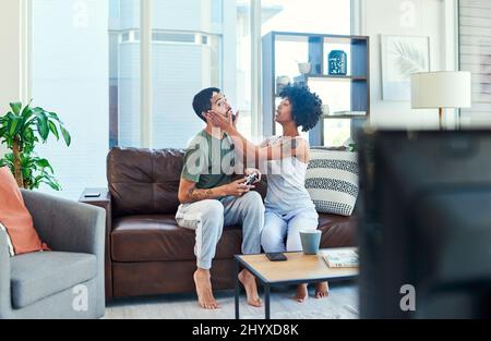 Stai andando a farmi perdere. Scatto di una donna che cerca di attirare l'attenzione dei suoi fidanzati mentre gioca video giochi. Foto Stock