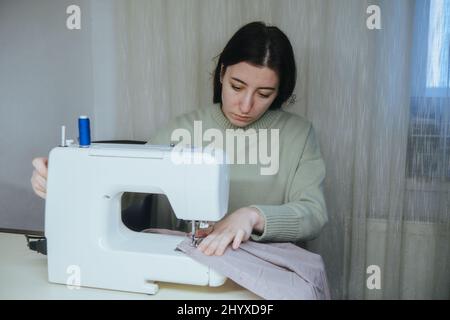 la donna sews su una macchina da scrivere a casa Foto Stock