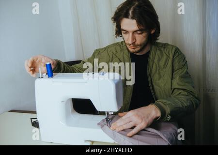 l'uomo sews su una macchina da scrivere in casa Foto Stock