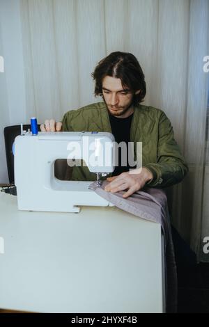 l'uomo sews su una macchina da scrivere in casa Foto Stock